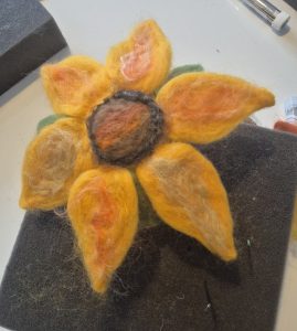 Felted sunflower, yellow wool, green leaves , felting in a teacup.